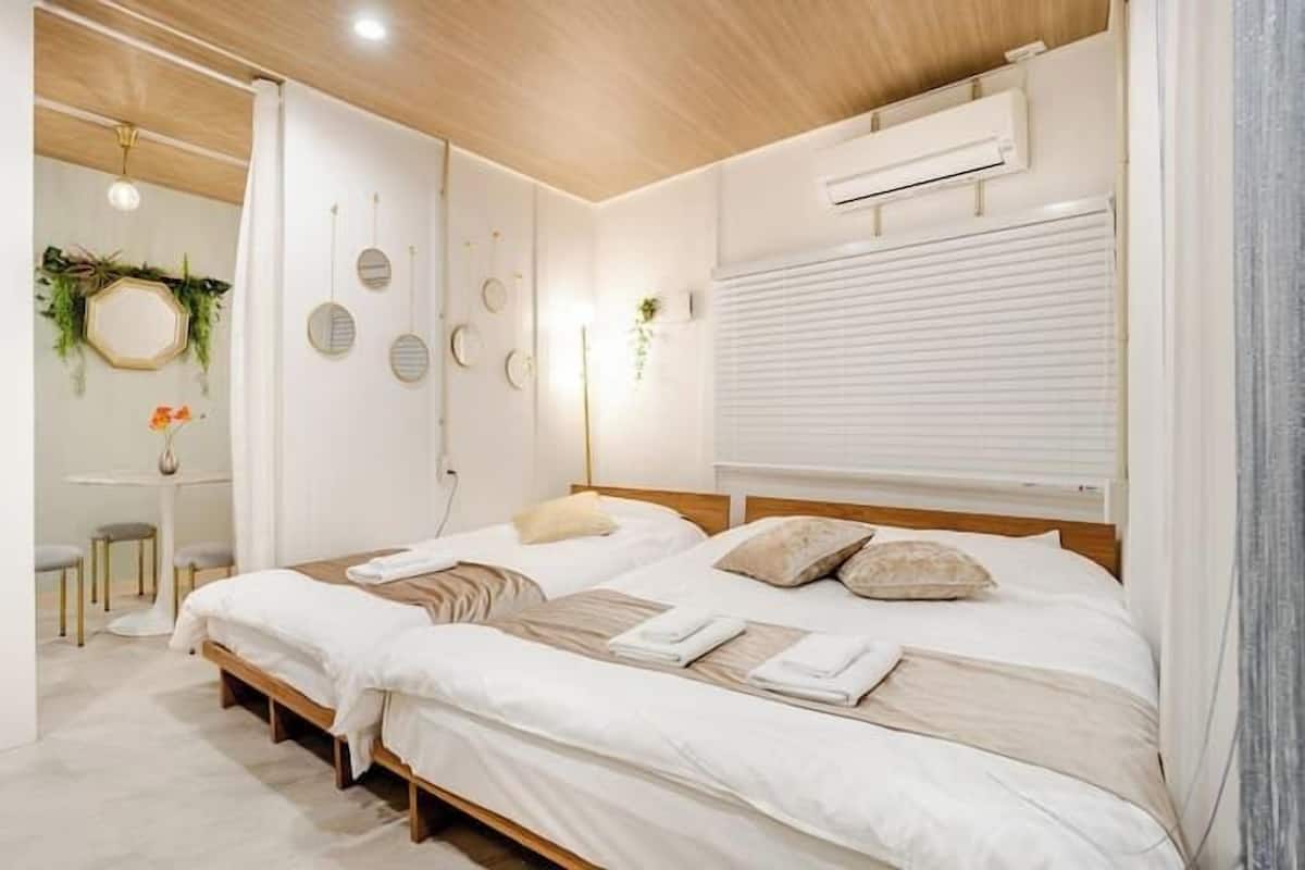 A modern bedroom with a large bed, bedside tables, and a wall-mounted air conditioning unit.