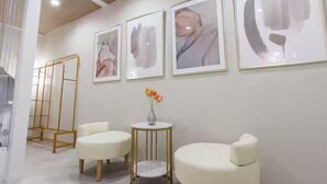 Ein modernes Interieur mit weißen Sofas, einem kleinen runden Tisch mit Blumenvase und abstrakter Kunst an der Wand.