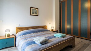 A bedroom with a wooden bed, two bedside tables with lamps, a wardrobe, and a framed picture on the wall. - Camelia by Interhome (Verbania)