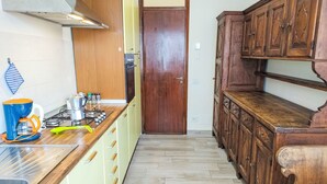A kitchen with a gas stove, a coffee maker, and wooden cabinets. - Camelia by Interhome (Verbania)