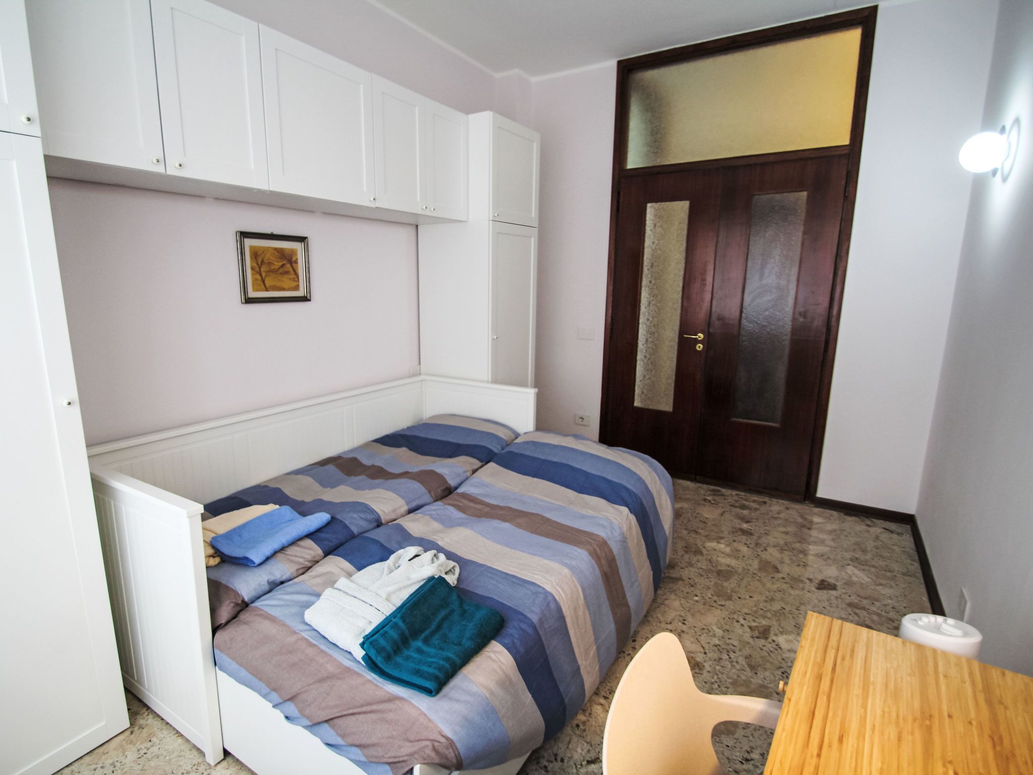 A compact room with a bed, a wooden table, and a door.