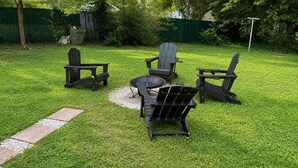 An outdoor seating area with Adirondack chairs and a fire pit.