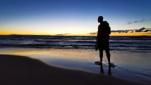 A person standing on a beach during sunset.