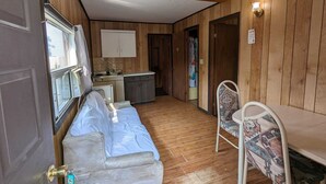 A compact RV interior with a kitchenette, a bed, and a small dining area.