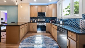 A modern kitchen with wooden cabinets, a stainless steel oven, and a blue-tiled backsplash. - Spacious Pittsburgh Home with Deck and Grill (Pittsburgh)