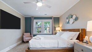 A bedroom with a bed, a nightstand, a chair, a window, and a ceiling fan. - Spacious Pittsburgh Home with Deck and Grill (Pittsburgh)