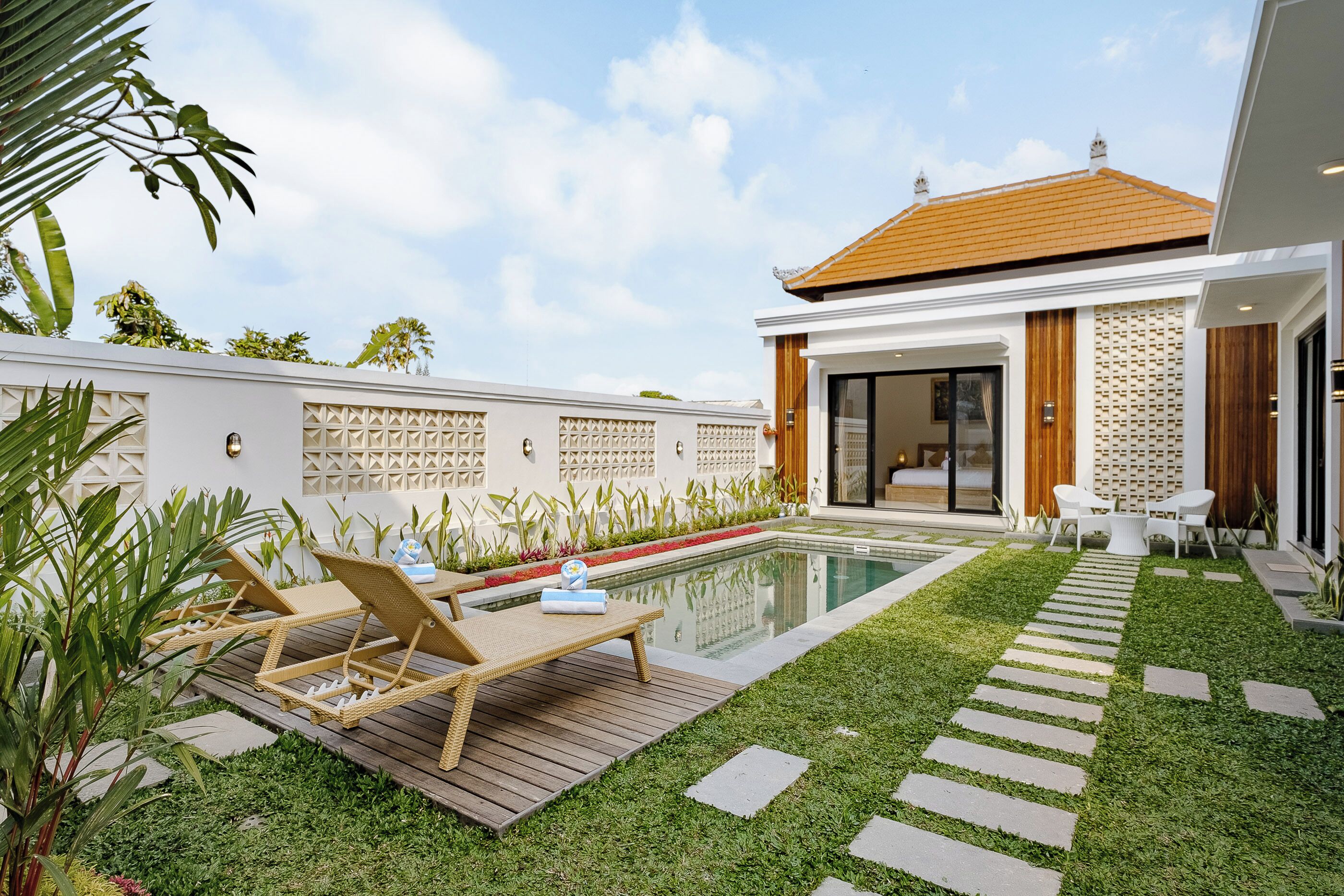 A modern house with a swimming pool, a wooden deck, and a well-maintained lawn.