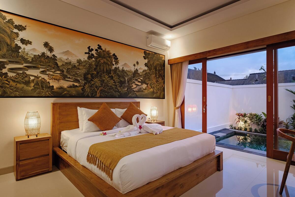 A well-appointed bedroom with a large bed, wooden headboard, and a painting above.