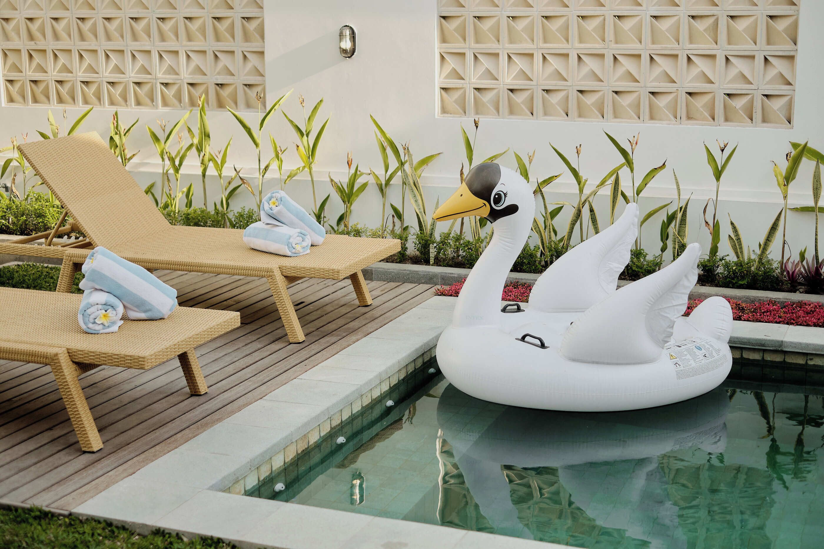 A pool area with lounge chairs and a swan float.