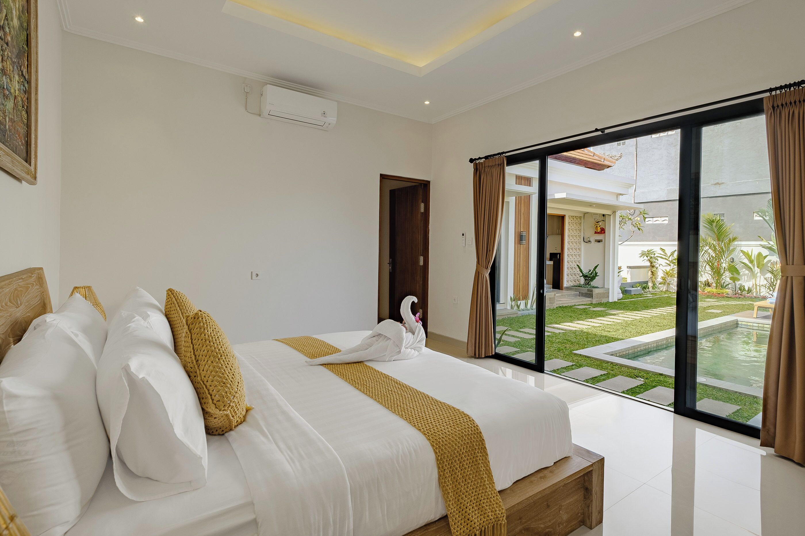 Une chambre d’hôtel avec un grand lit, une vue sur une piscine et une porte-fenêtre coulissante donnant sur un espace extérieur.