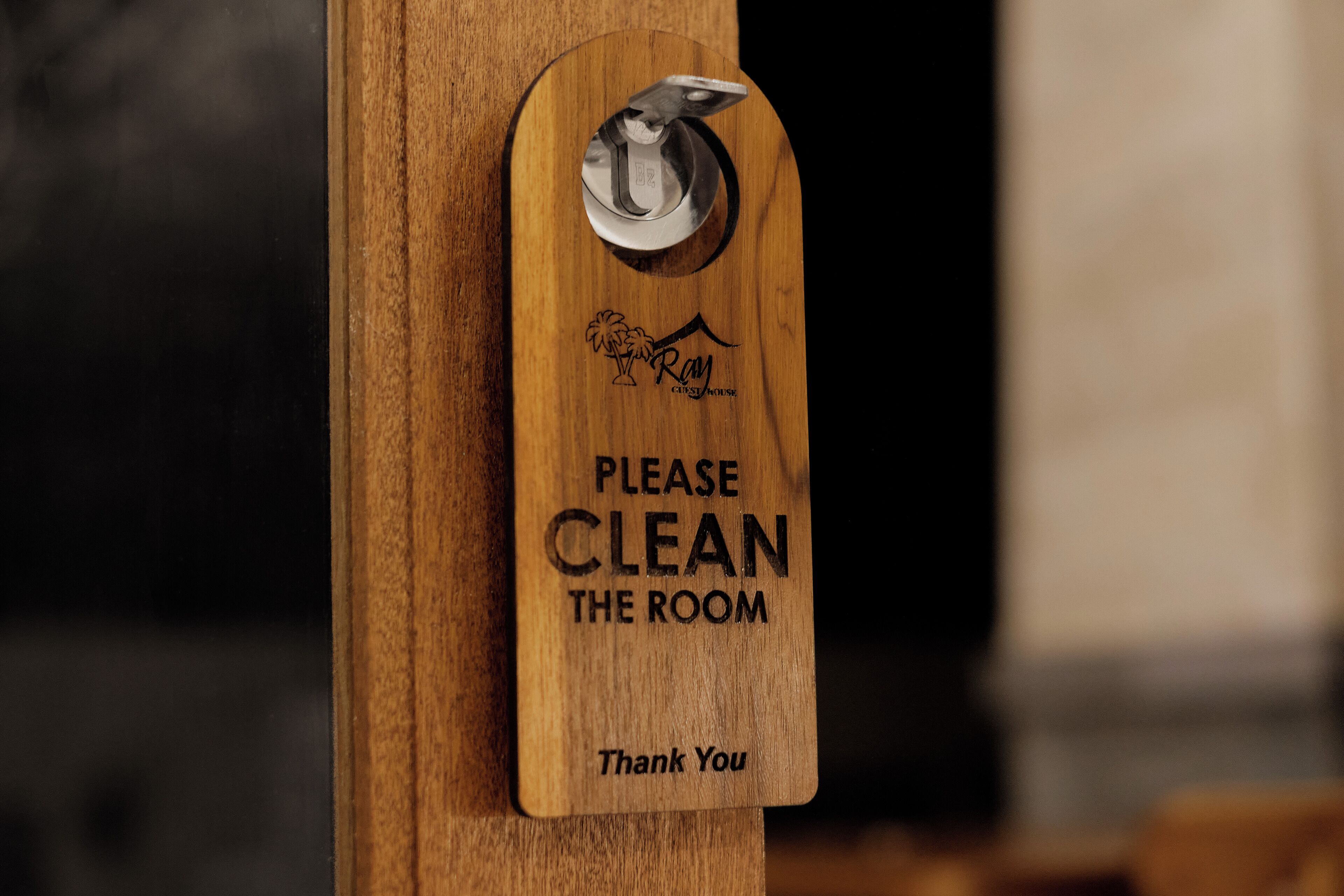 A wooden sign with a metal latch, requesting to clean the room and thanking guests.