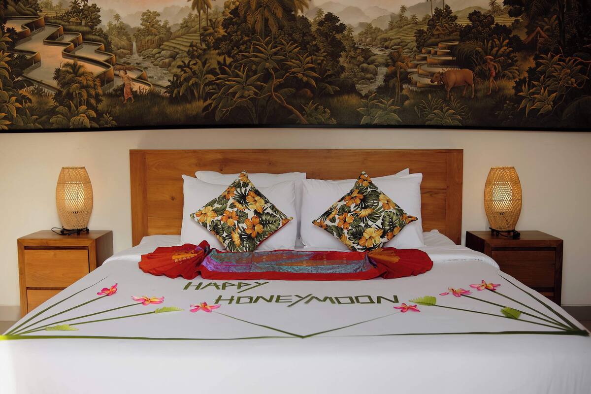 A hotel room with a bed, two nightstands, and a mural on the wall.