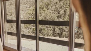 Una habitación con un ventanal grande, un banco de madera y una persona leyendo un libro.