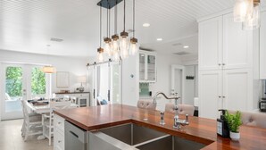 Una cocina moderna con una isla central, electrodomésticos de acero inoxidable e iluminación colgante.