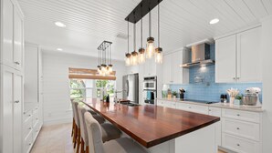 Una cocina moderna con armarios blancos, una isla de madera e iluminación colgante.