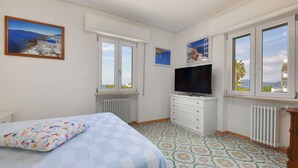 Makuuhuoneessa on sänky, lipasto, televisio ja kaksi ikkunaa, joista avautuu näkymä rannikkomaisemaan.