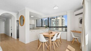 A modern apartment with a kitchen, dining area, and a balcony with a city view. - Carrington Family Beach Getaway - Ocean View, WiFi (Main Beach)