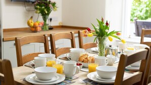 Et morgenbord dækket til fire personer, med croissanter, appelsinjuice og kaffekopper.