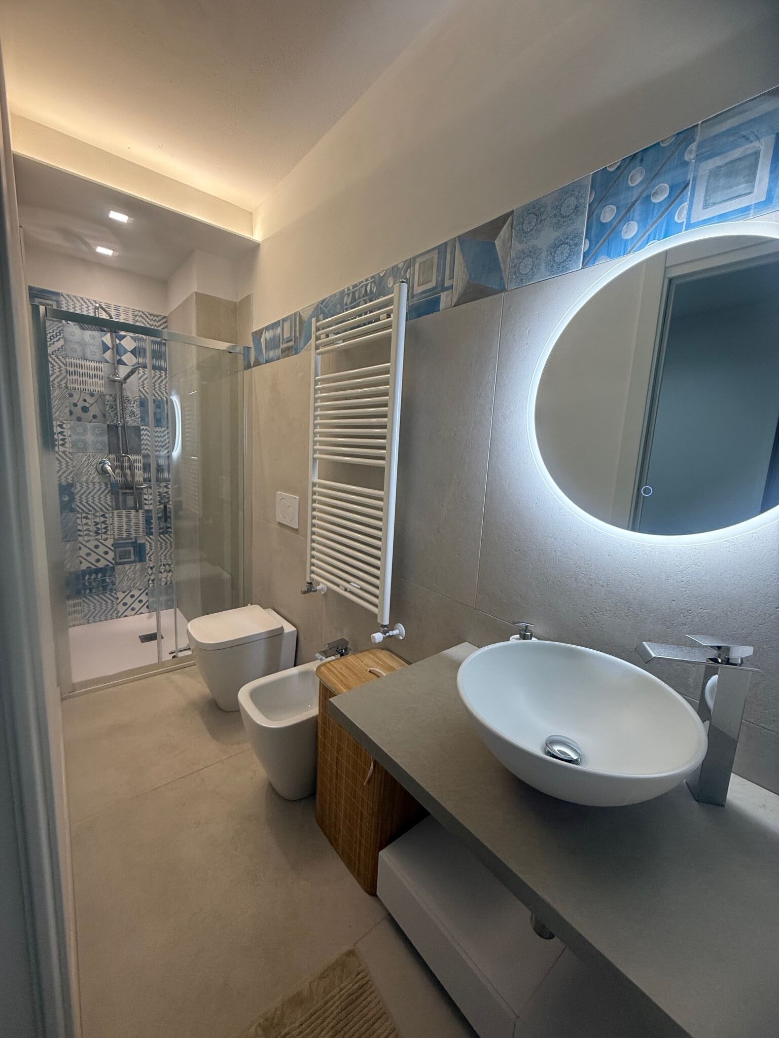 Un bagno moderno con doccia vetro, bidet, lavandino capiente e specchio.