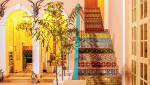 Un escalier orné de carreaux colorés, une plante verte et une statue de chien.