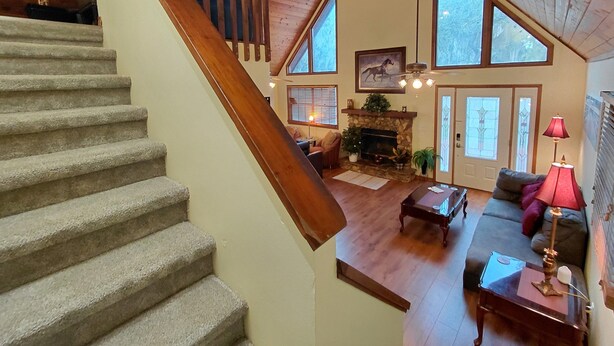 A staircase leading to a living area with a fireplace, large windows, and a cozy seating arrangement. - Unique A-Frame wloft, pool, & RV electric 17 min from Silver Springs State Park  (Silver Springs)