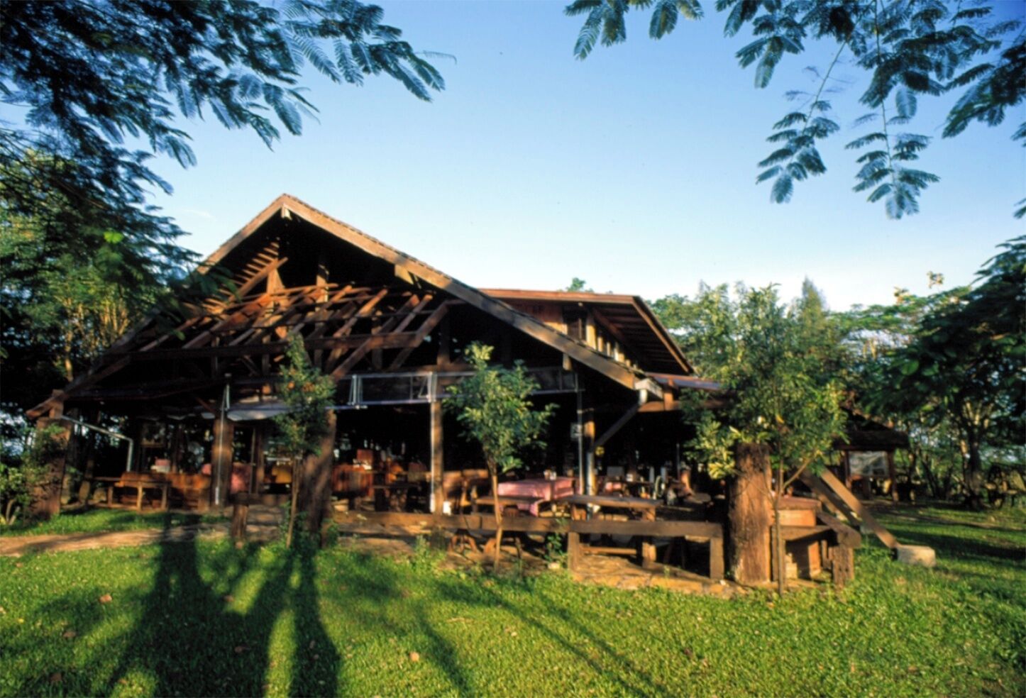 Un bâtiment rustique en bois, doté d’un toit en pente, entouré d’une végétation luxuriante et d’arbres.