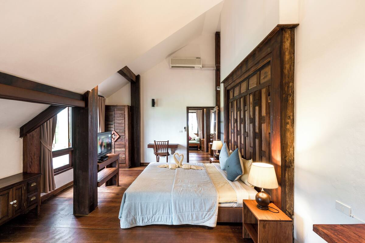 Un dormitorio amplio con una cama grande, muebles de madera y un televisor.