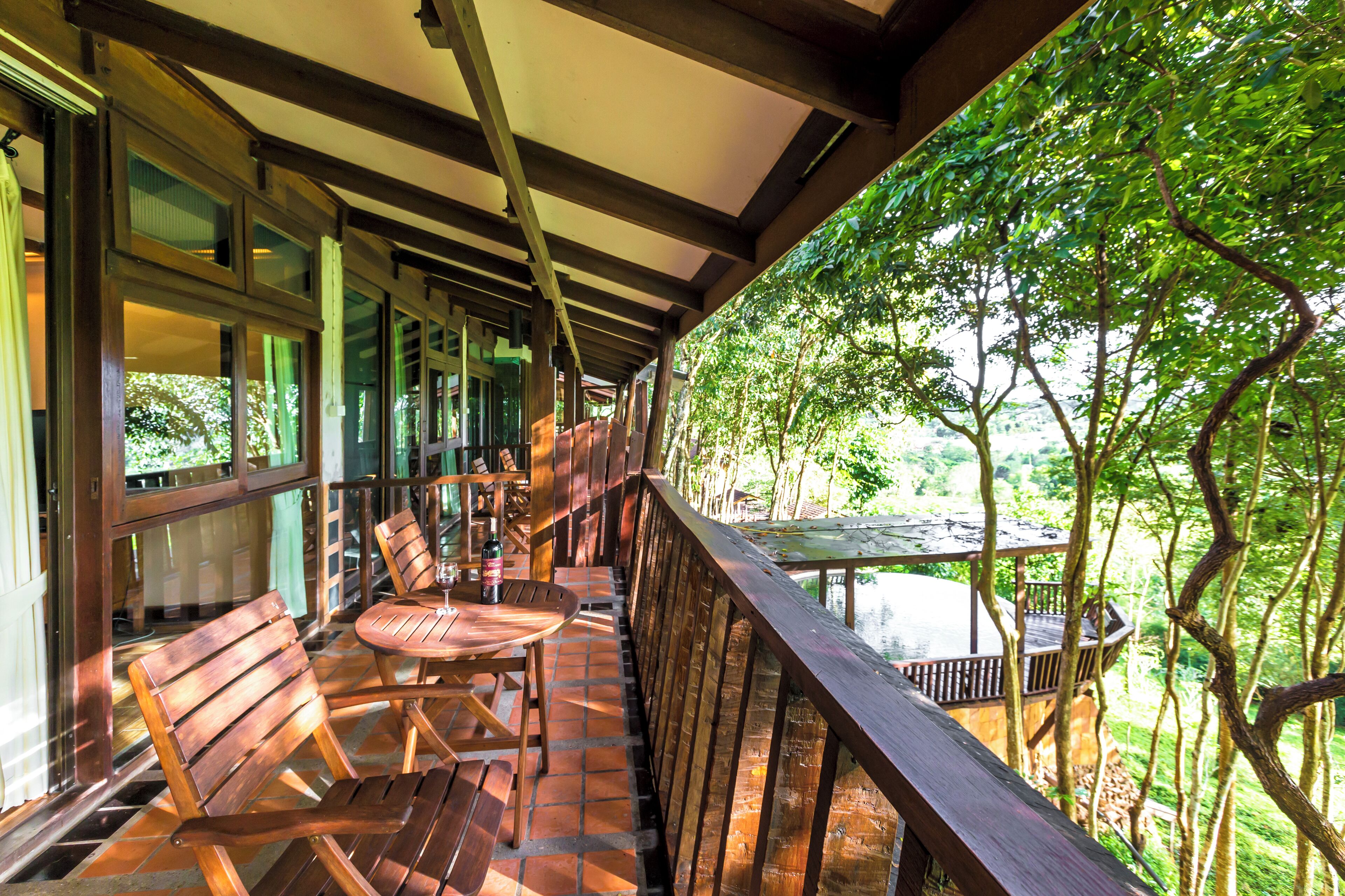 Une terrasse en bois avec une table et des chaises, donnant sur une étendue d’eau et entourée d’arbres.