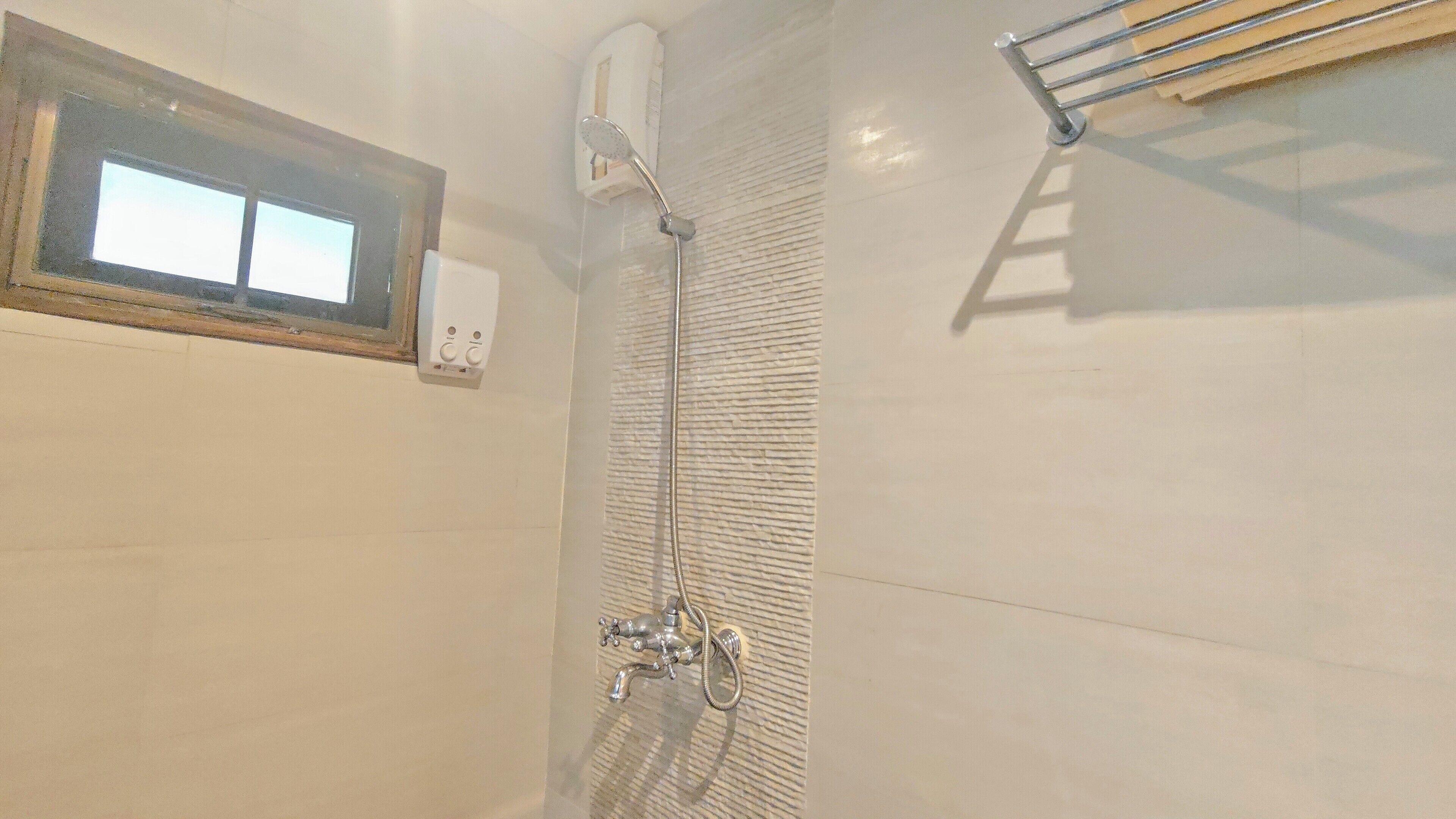 Un baño con ducha, una ventana y un perchero para toallas.