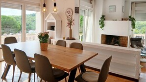 A dining area with a wooden table and chairs, a vase with flowers, and a fireplace. - Holiday home with private pool in L'Escala. HUTG-011949 (l'Escala)