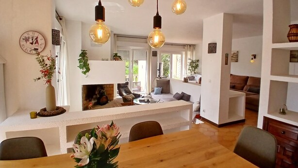 A modern living room with a wooden dining table, a fireplace, and hanging light fixtures. - Holiday home with private pool in L'Escala. HUTG-011949 (l'Escala)