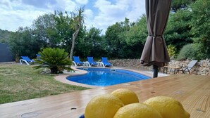A wooden table with a plate of lemons, a pool, and blue lounge chairs in the background. - Holiday home with private pool in L'Escala. HUTG-011949 (l'Escala)