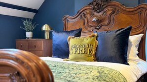 A bedroom with a wooden bed, a green patterned bedspread, and a headboard with intricate carvings. - Charming Grade 2 Listed Apartment in Alnwick town centre with castle views. (Alnwick)