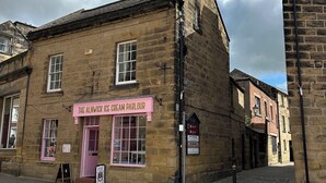 A traditional stone building with a pink awning labeled "The Alnwick Ice Cream Parlour." - Charming Grade 2 Listed Apartment in Alnwick town centre with castle views. (Alnwick)