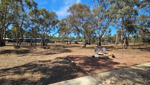 An outdoor area with trees, a concrete path, and two chairs. - Pet Friendly Relax with the whole family or friends. (Axedale)