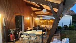 An outdoor patio with a wooden deck, a round table, and chairs. - House with swimming pool near Contis beach, cycle path and all amenities (Saint-Julien-en-Born)