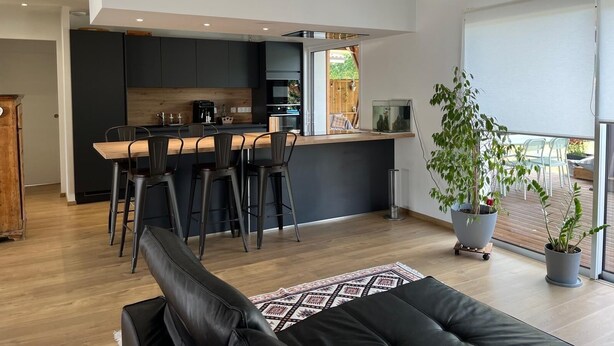 A modern kitchen with a central island, black bar stools, and a hanging pendant light. - House with swimming pool near Contis beach, cycle path and all amenities (Saint-Julien-en-Born)