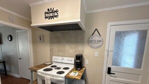 A compact kitchen with a stove, coffee maker, and a sign indicating a coffee bar.
