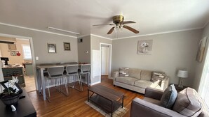 A modern living room with a dining area, a sofa, a coffee table, and a ceiling fan.