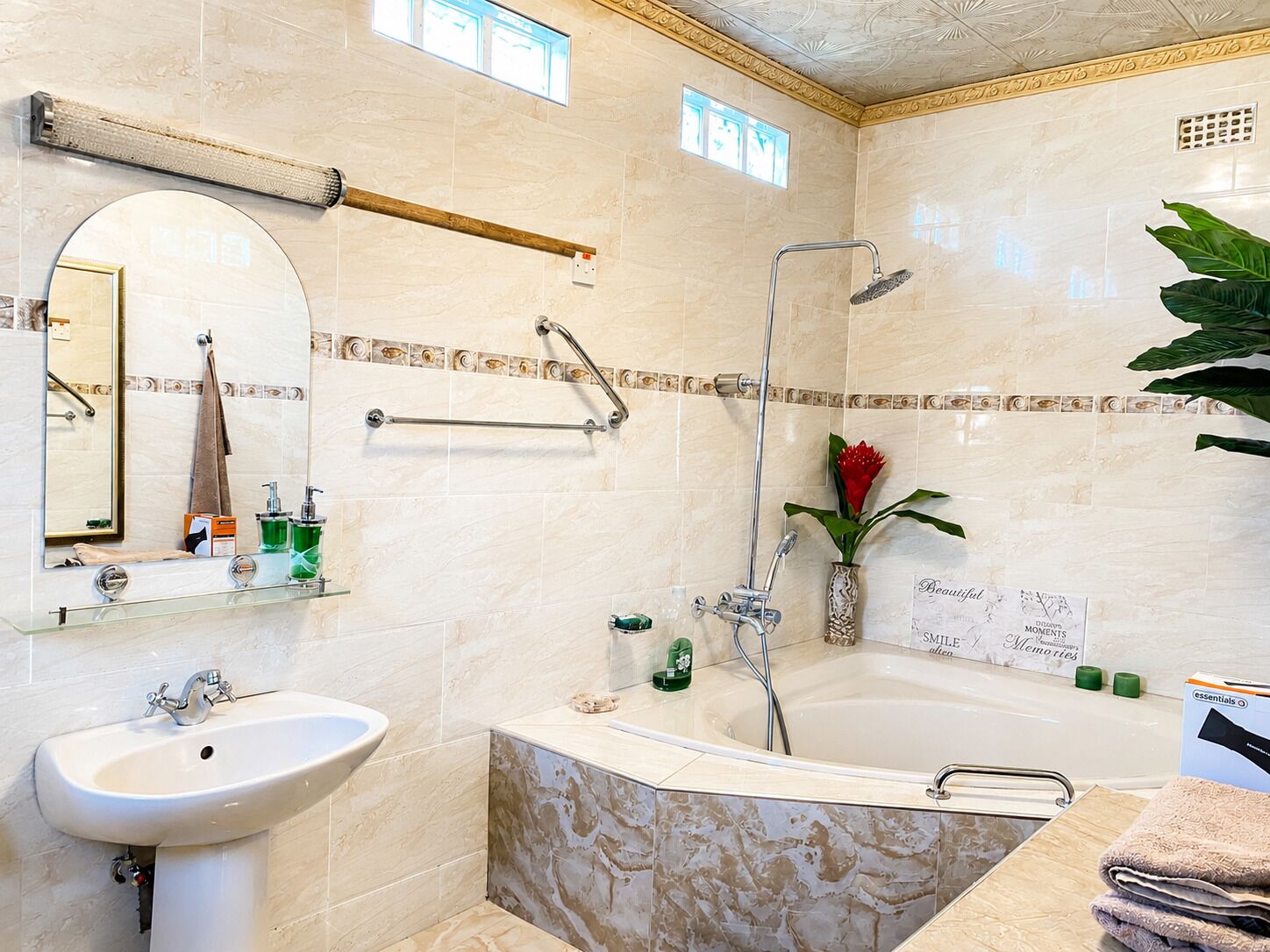 A bathroom with a sink, mirror, towel rack, shower, and a decorative sign.