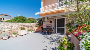 Eine Terrasse mit Sitzgelegenheiten im Freien, einer Steinsäule und Kübelpflanzen.