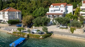 A coastal property with a dock, parked cars, and a stone wall. - Apartman Marija Slano by Villas Guide (Slano)