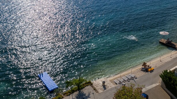 A coastal area with a clear view of the sea, a paved walkway, and beach chairs. - Apartman Marija Slano by Villas Guide (Slano)