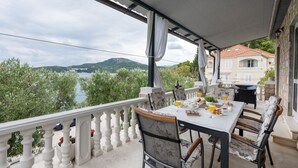 A balcony with a table set for breakfast, overlooking a lake and hills. - Apartman Marija Slano by Villas Guide (Slano)