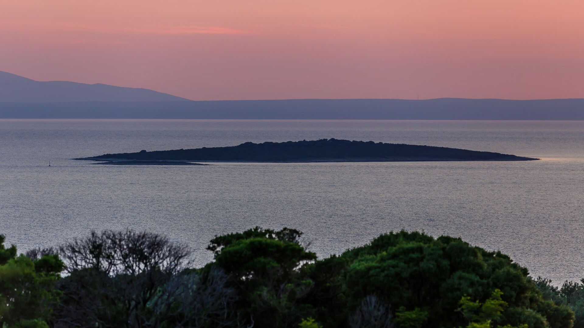 A coastal view with a distant island and a clear sky.