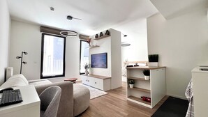 Un salon moderne avec un canapé, un téléviseur fixé au mur et un plancher en bois.