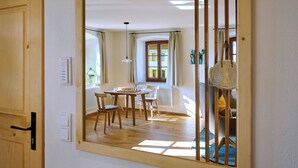 A dining area with a wooden table, chairs, and a view of the outside through a window.
