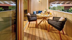 Um deck de madeira com uma mesa redonda e cadeiras de vime, com vista para um jardim.