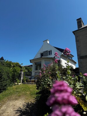 Set amidst lush greenery, this charming house features a gabled roof and an entrance.
