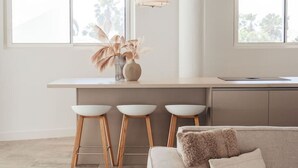 A modern kitchen with a bar area, a sofa, and a dining table. - LUX 2BD Condo | ONE Mambo Beach 3 by Bocobay (Willemstad)